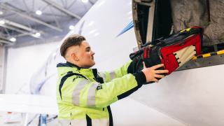 Varian logistiikan opiskelija pakkaamassa lentokoneen tavaratilaa.