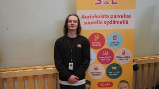 Leevi seisoo SOL-kyltin vieressä rekrymessuilla.